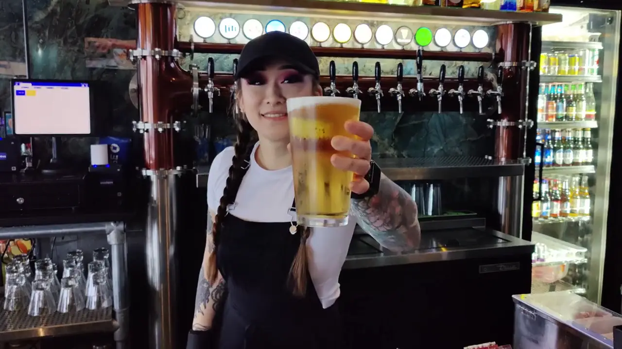 Bartender holding a fresh pint in front of the tap wall at Lefty's cocktail bar in San Antonio